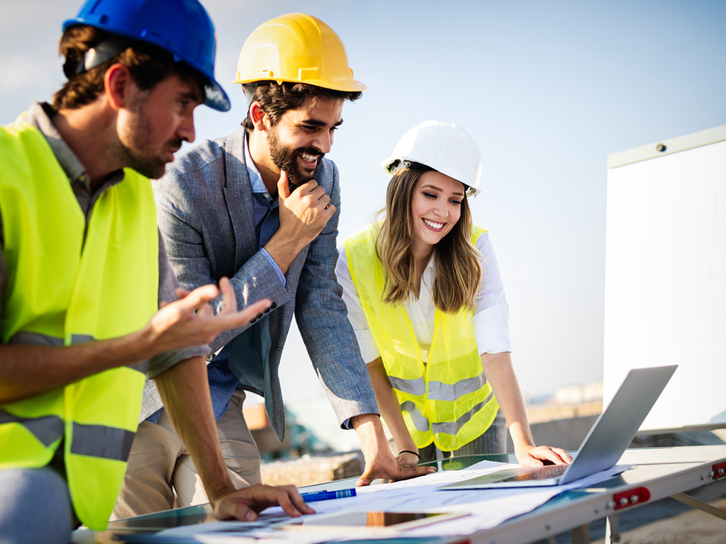 a group of workers outside looking at their laptop